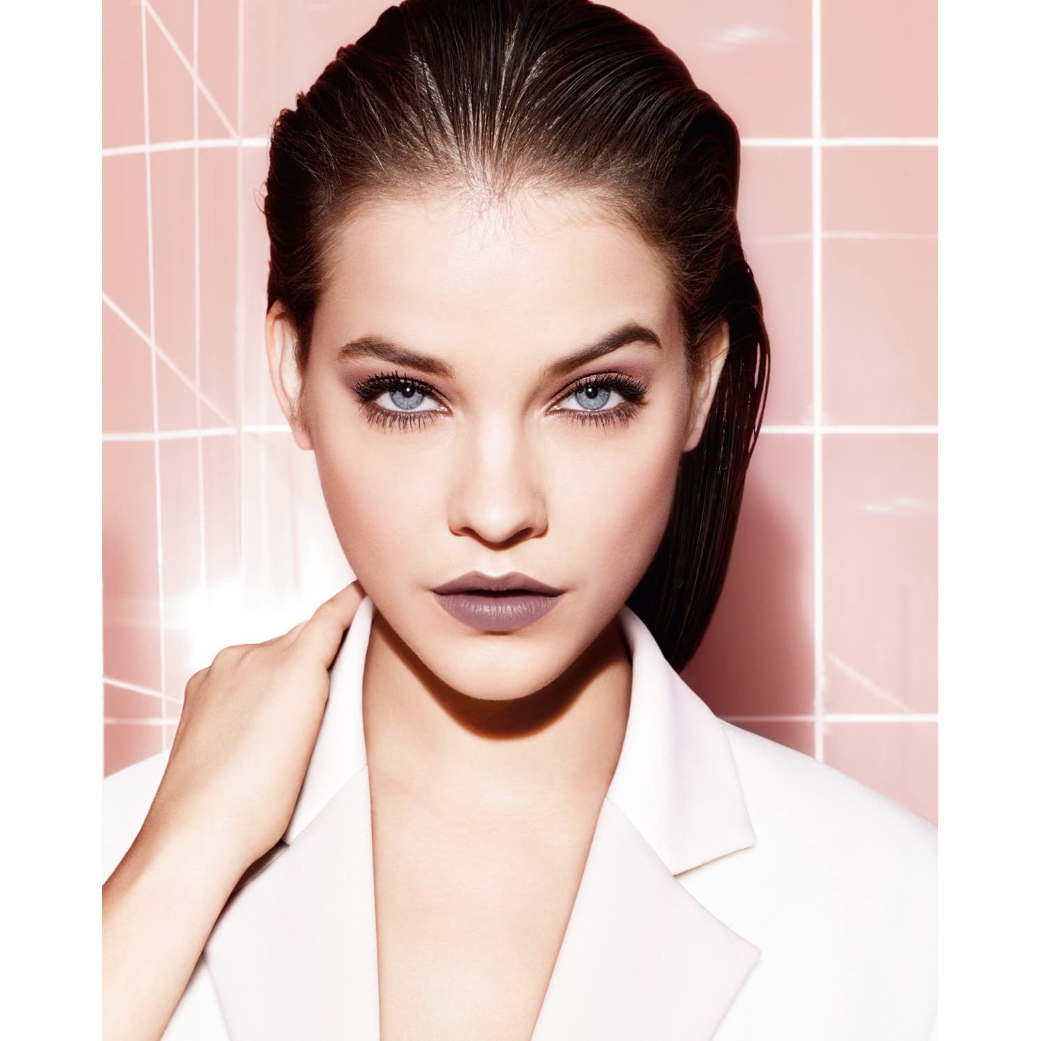Woman with stylish hair and makeup against a pink tiled wall